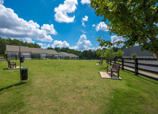 a park with benches in front of a fenced in field