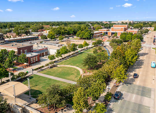 A view of a campus with a green field and buildings.