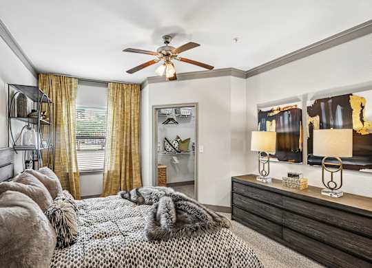 A bedroom with a bed covered in a fur throw and a ceiling fan.