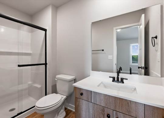 A modern bathroom with a toilet, sink, and mirror.
