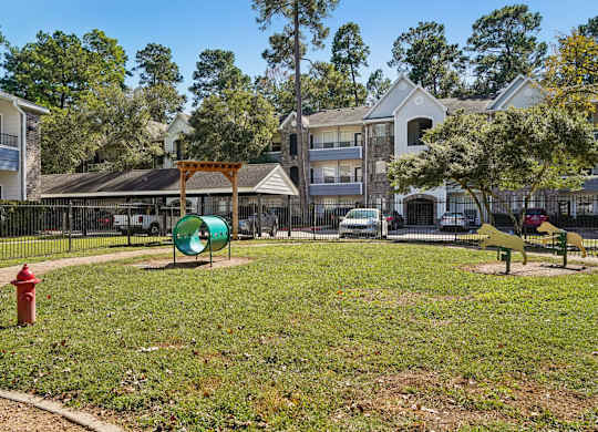 A park with a red fire hydrant and a green playground.