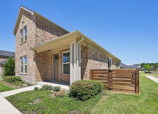A house with a brown brick exterior and a wooden fence.