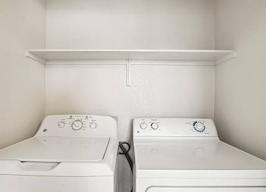 Two white washing machines in a small laundry room.
