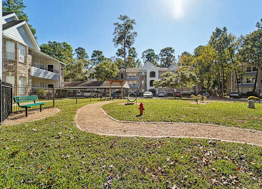 A sunny day at a park with a playground and apartment buildings in the background.