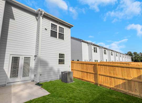 A grey house with a brown fence and a green lawn.