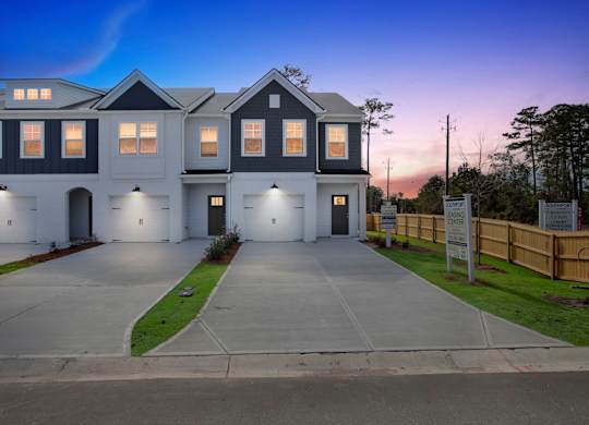 A modern two-story house with a large front yard and a driveway.