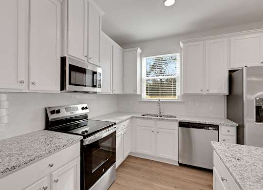A kitchen with white cabinets and appliances.