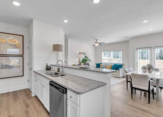 A modern kitchen with a dining area in the background.