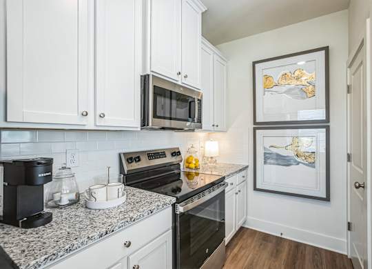 A kitchen with a granite countertop and white cabinets.