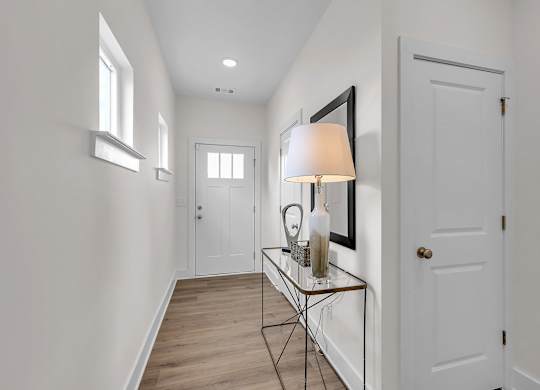 A hallway with a table and a lamp.