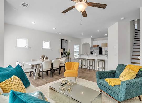 A living room with a blue chair and yellow pillow.