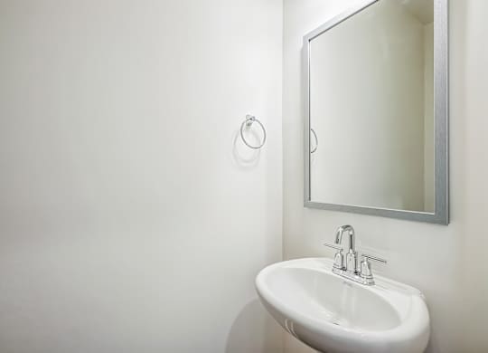 A white sink in a bathroom with a mirror above it.