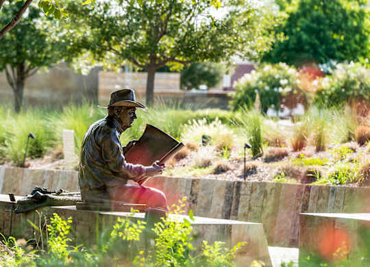 A statue of a man sitting and reading a book.