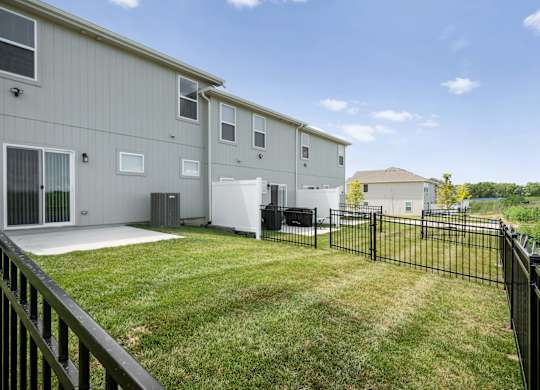 Apartment complex with a black fence and green grass.