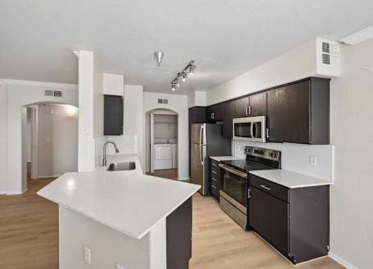 A kitchen with a white island and black appliances.