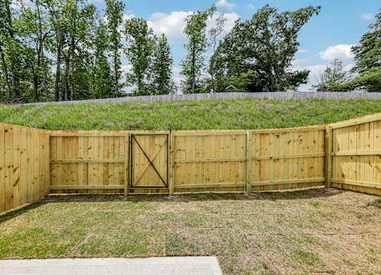 A wooden fence encloses a grassy area with a gate in the middle.
