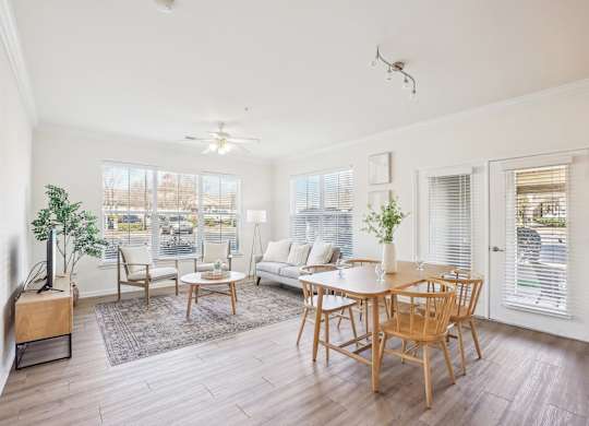 A living room with a white couch, wooden chairs, and a television.