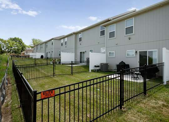 A black fence with an Elite sign in front of apartment buildings.