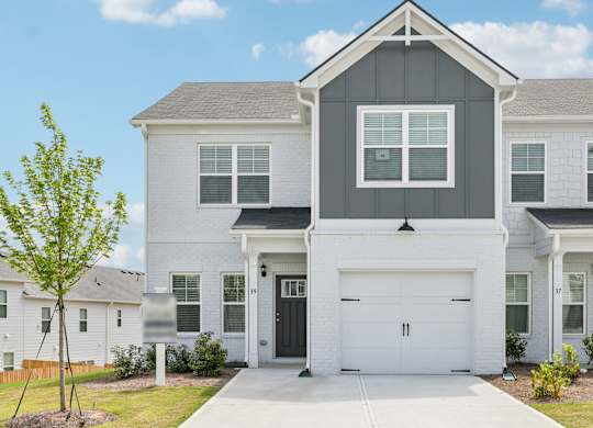 A white house with a black garage door in front.