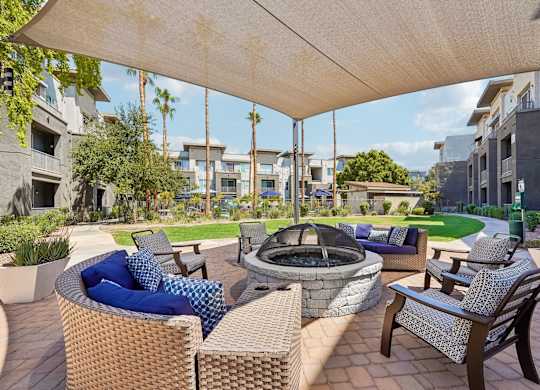 A patio with a fire pit and chairs under a canopy.