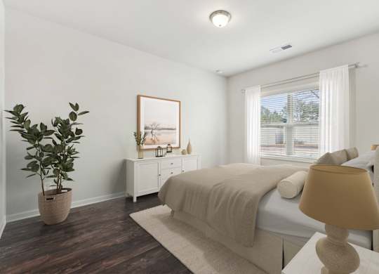 A bedroom with a bed, nightstand, and a plant.