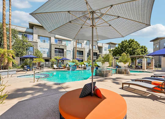 A sunny day at the pool with a blue umbrella and a white umbrella.