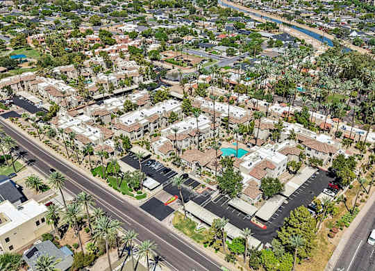 A bird's eye view of a residential area with houses, roads, and palm trees.