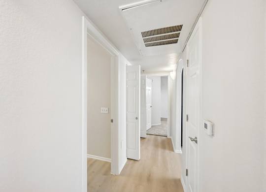 A long hallway with white walls and wood flooring.