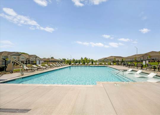 A large swimming pool with lounge chairs and a clear blue sky.