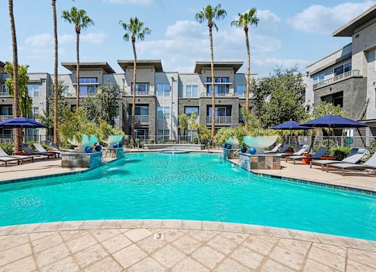 A swimming pool surrounded by palm trees and lounge chairs.