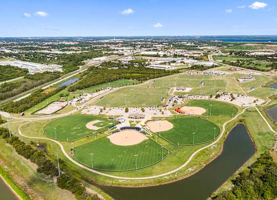 A large green field with a baseball diamond and a basketball court.