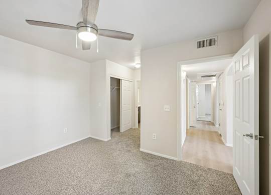 A room with a ceiling fan and carpeted floor.