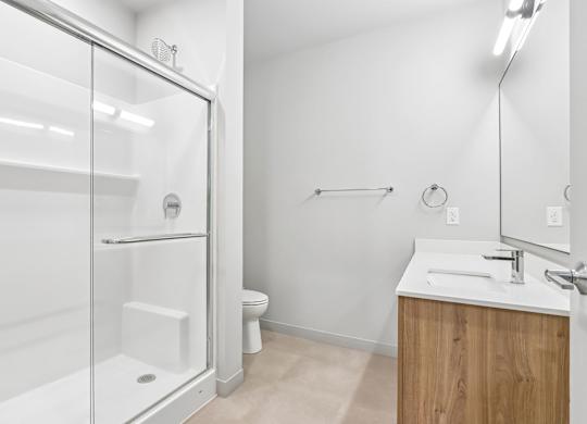 A white bathroom with a walk in shower and a sink.