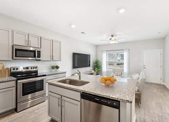 A modern kitchen with stainless steel appliances and a marble countertop.