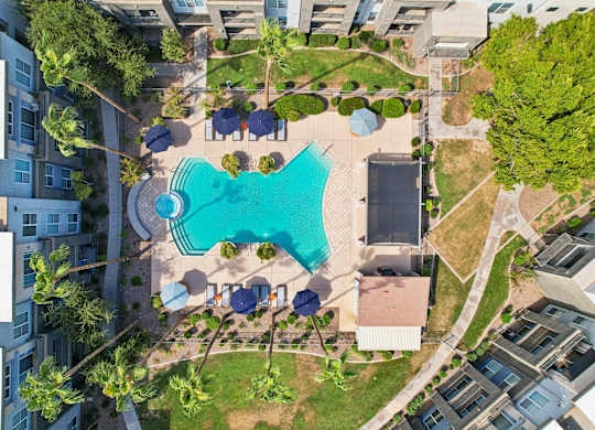 An aerial view of a swimming pool surrounded by buildings and trees.