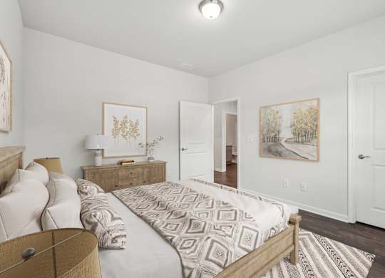A bedroom with a large bed and two paintings on the wall.