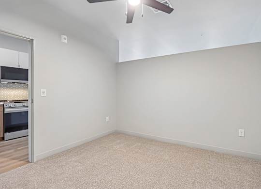 A room with a ceiling fan and carpeted floor.