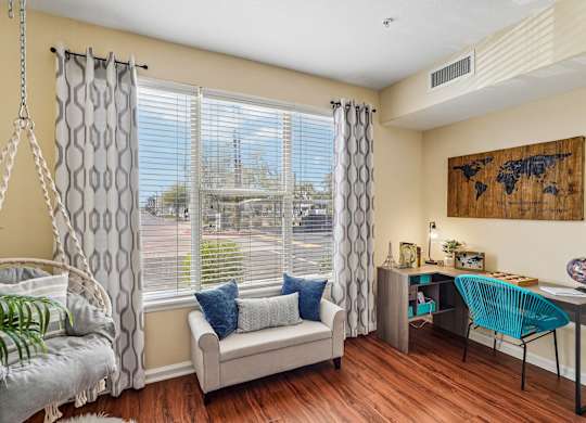 A room with a hanging chair and a couch with a window behind it.