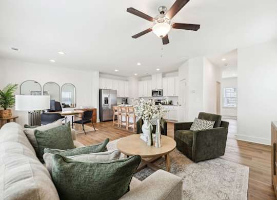 A living room with a white ceiling fan and a grey rug.