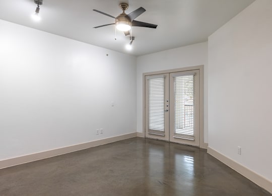 A room with a ceiling fan and sliding glass doors.