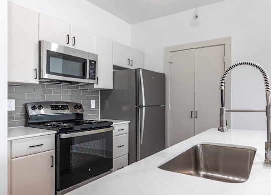 A kitchen with a stove, refrigerator, and microwave.