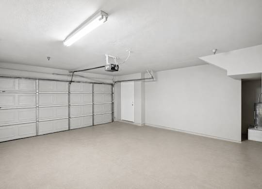 A spacious garage with a closed white door and a white ceiling.
