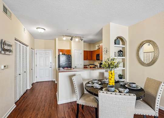 A dining room with a table set for two and a television in the background.