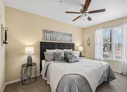 A bedroom with a large bed and a ceiling fan.