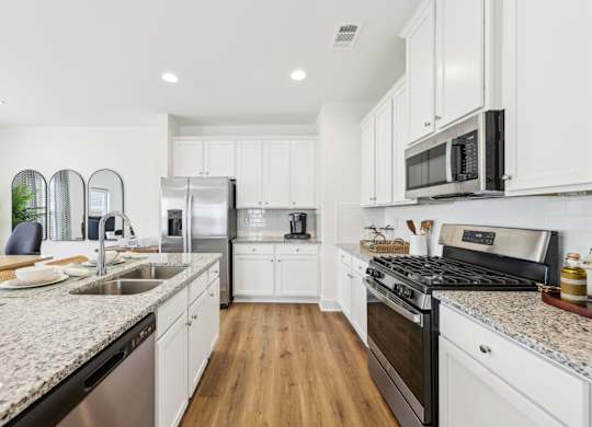 A modern kitchen with white cabinets and stainless steel appliances.