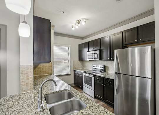 A modern kitchen with a stainless steel refrigerator and black cabinets.