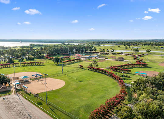 A beautifully maintained park with a baseball field and a tennis court.
