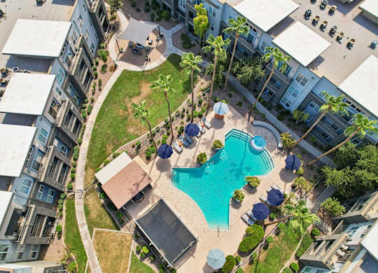 A swimming pool surrounded by a grassy area and a few trees.