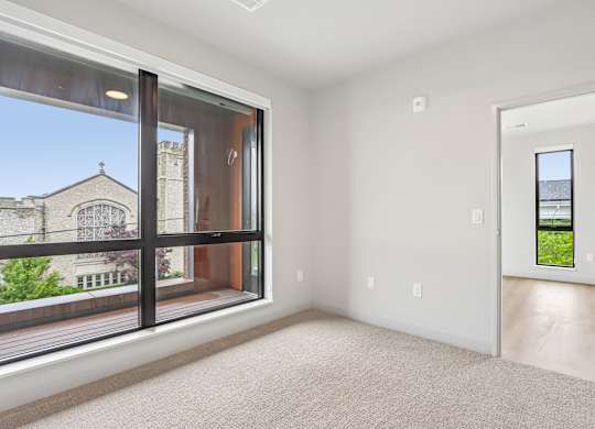 A large empty room with a view of a building outside through the window.