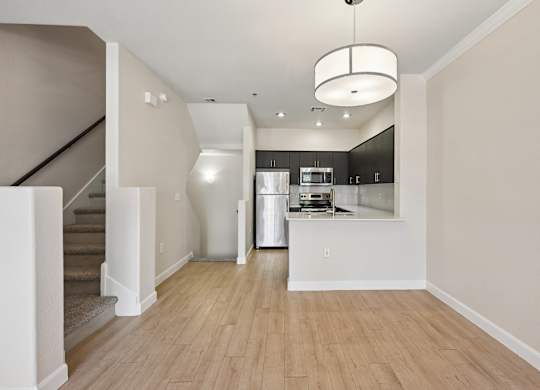 A modern kitchen with a staircase leading to the upper floor.